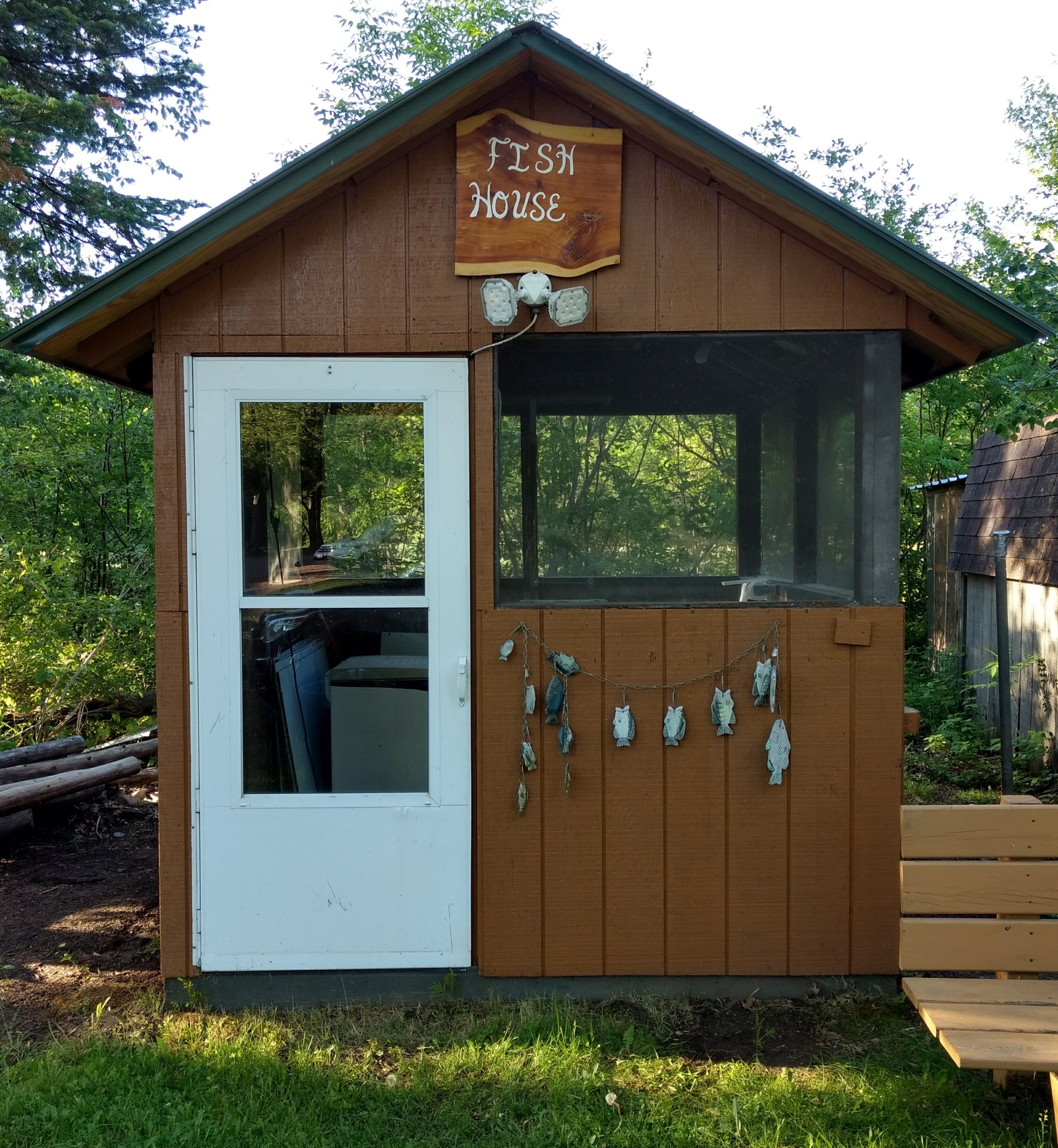 Une structure en bois portant l’inscription « Maison des poissons », avec une porte, des fenêtres et des décorations représentant des poissons.