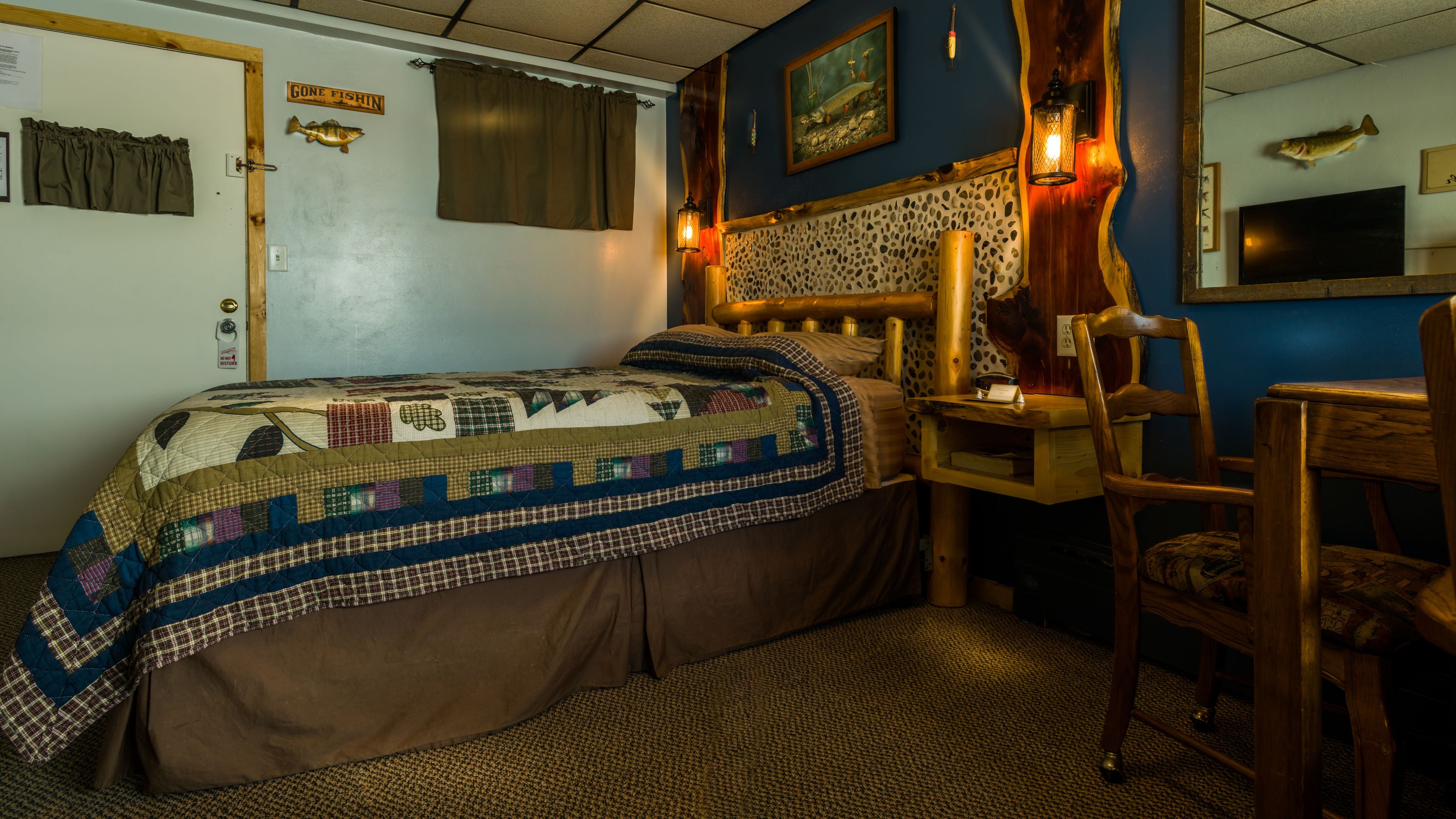 Ein gemütliches Zimmer mit einem Bett, einem Holztisch, einem Stuhl und Fischmotiven.