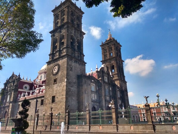 Una iglesia histórica con dos torres destacadas, un gran reloj y una fuente en primer plano.