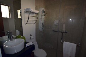 A bathroom with a sink, toilet, and glass-enclosed shower. - Suites La Concordia (Puebla)