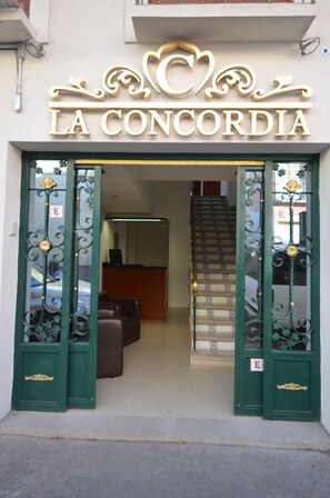 La entrada de La Concordia, con puertas verdes ornamentadas y una escalera que conduce al interior.