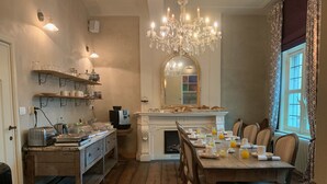 Una cocina acogedora con muebles de madera, un candelabro y una mesa de comedor preparada para el desayuno.