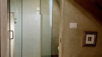 Een badkamer met een glazen douchedeur, een witte badkuip en een betegelde vloer.