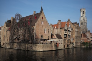 A historic building with a prominent tower, situated by a river.