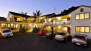 A multi-story hotel with a parking lot. - Whangaparaoa Lodge Motel (Whangaparaoa)