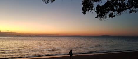 A beach scene with a person walking along the shore.