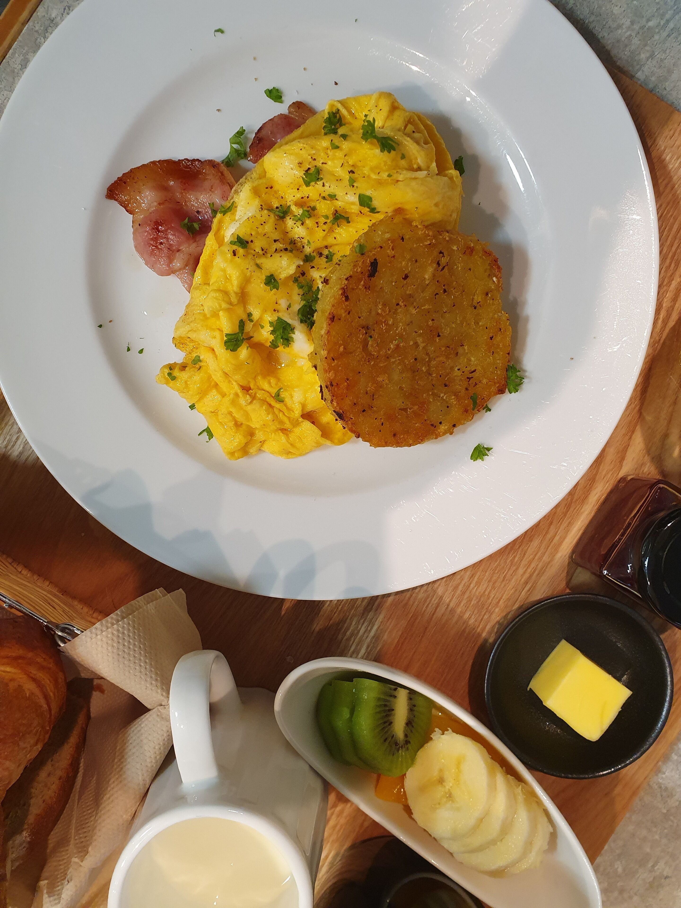 Um prato com ovos mexidos, bacon e hash browns.
