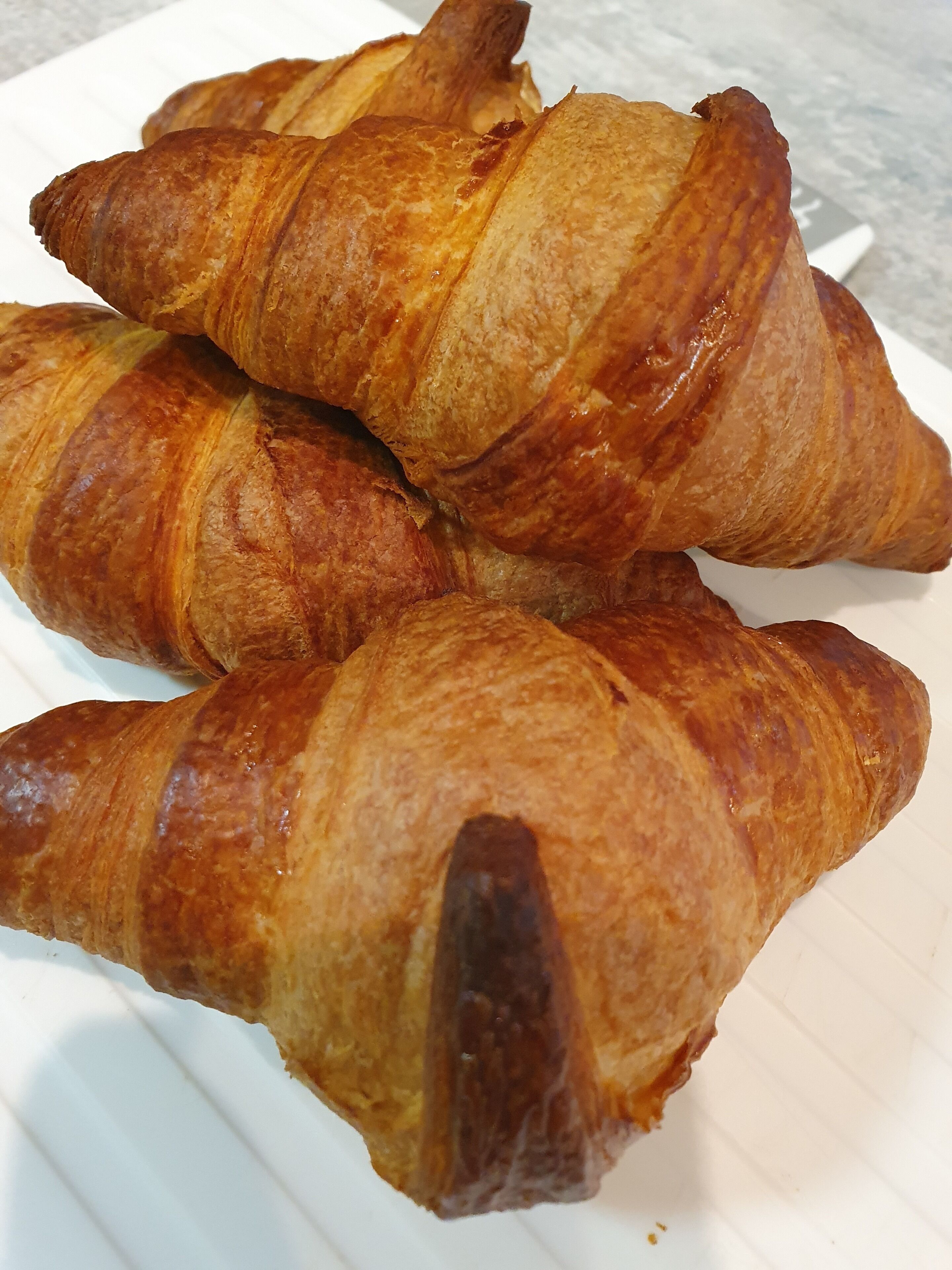 Four croissants on a white plate.