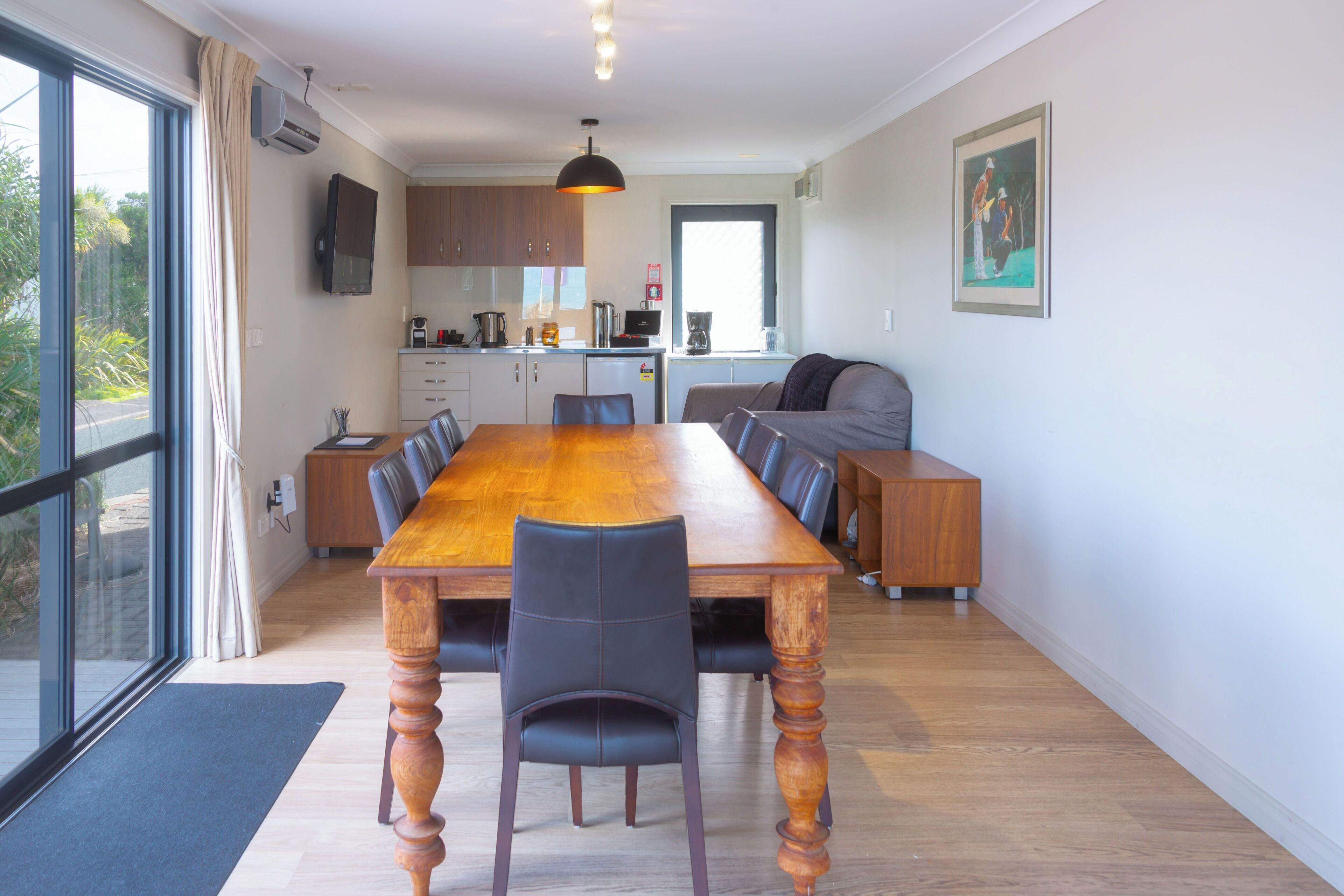 Une cuisine moderne avec des meubles en bois, une grande table à manger et une vue sur l’extérieur.