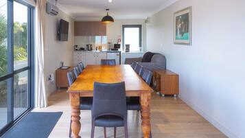 Une cuisine moderne avec des meubles en bois, une grande table à manger et une vue sur l’extérieur.