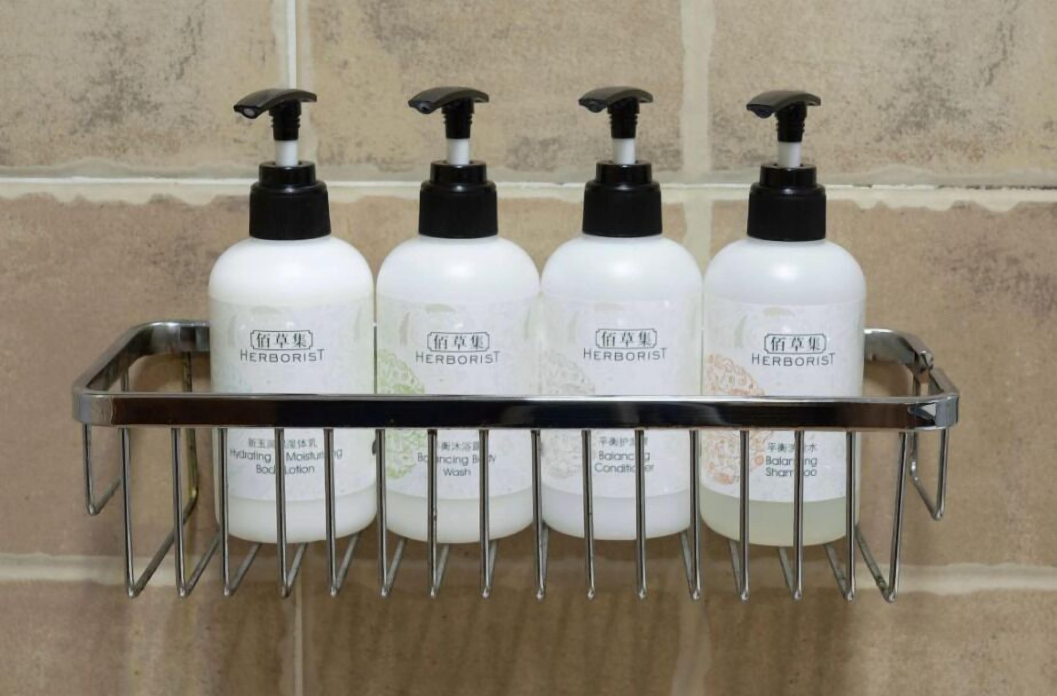 Cuatro botellas de loción corporal 'Herborist', gel de baño hidratante, gel de ducha equilibrante y acondicionador equilibrante, todas con dosificadores negros, dispuestas sobre una rejilla metálica frente a una pared de azulejos.
