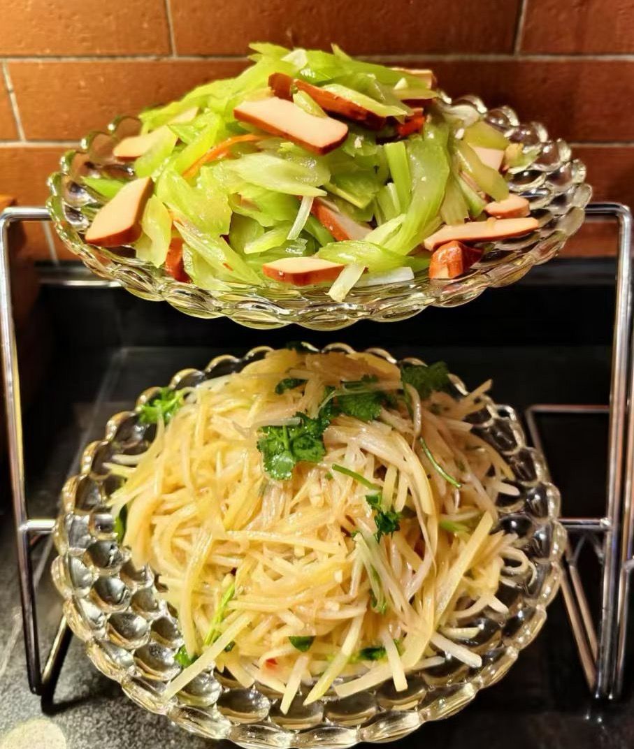 Twee glazen schalen met eten, één met groene groenten en de ander met noedels.