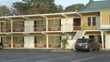 Um motel com estrutura em dois andares, estacionamento e um veículo estacionado na frente.