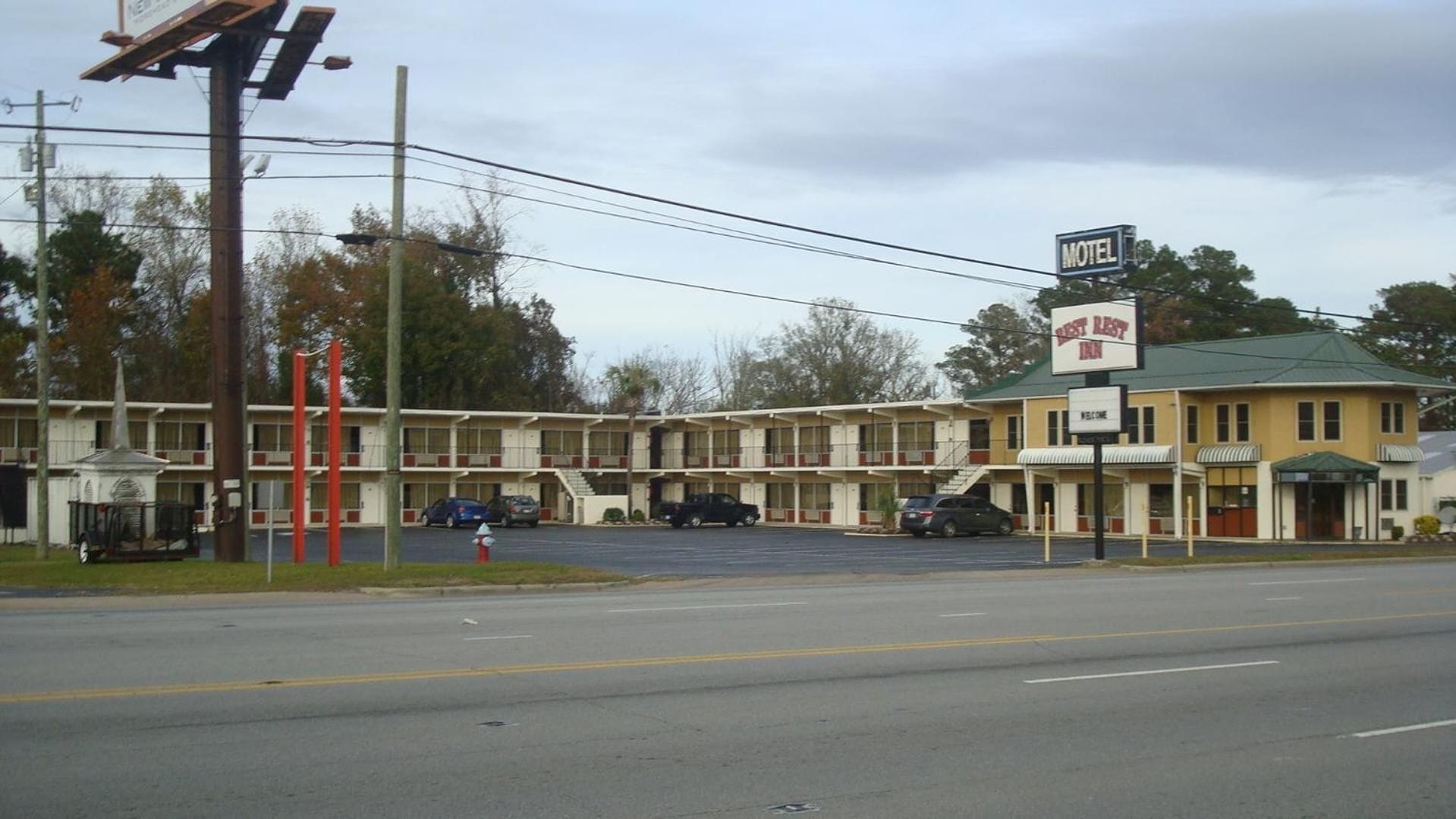 Un motel avec un bâtiment à deux étages, un toit végétalisé et une enseigne « Bienvenue ».