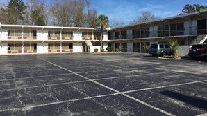 Un motel con diversi piani, un parcheggio e alcune automobili parcheggiate.