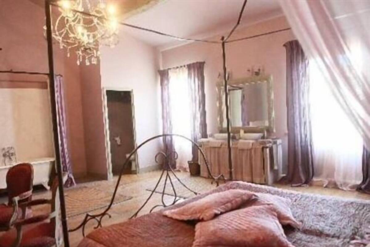 Een kamer met een bed, een stoel, een bureau en een spiegel.