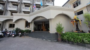 A multi-story building with a grand entrance, balconies, and flags. - Honey Lodge (Pattaya)