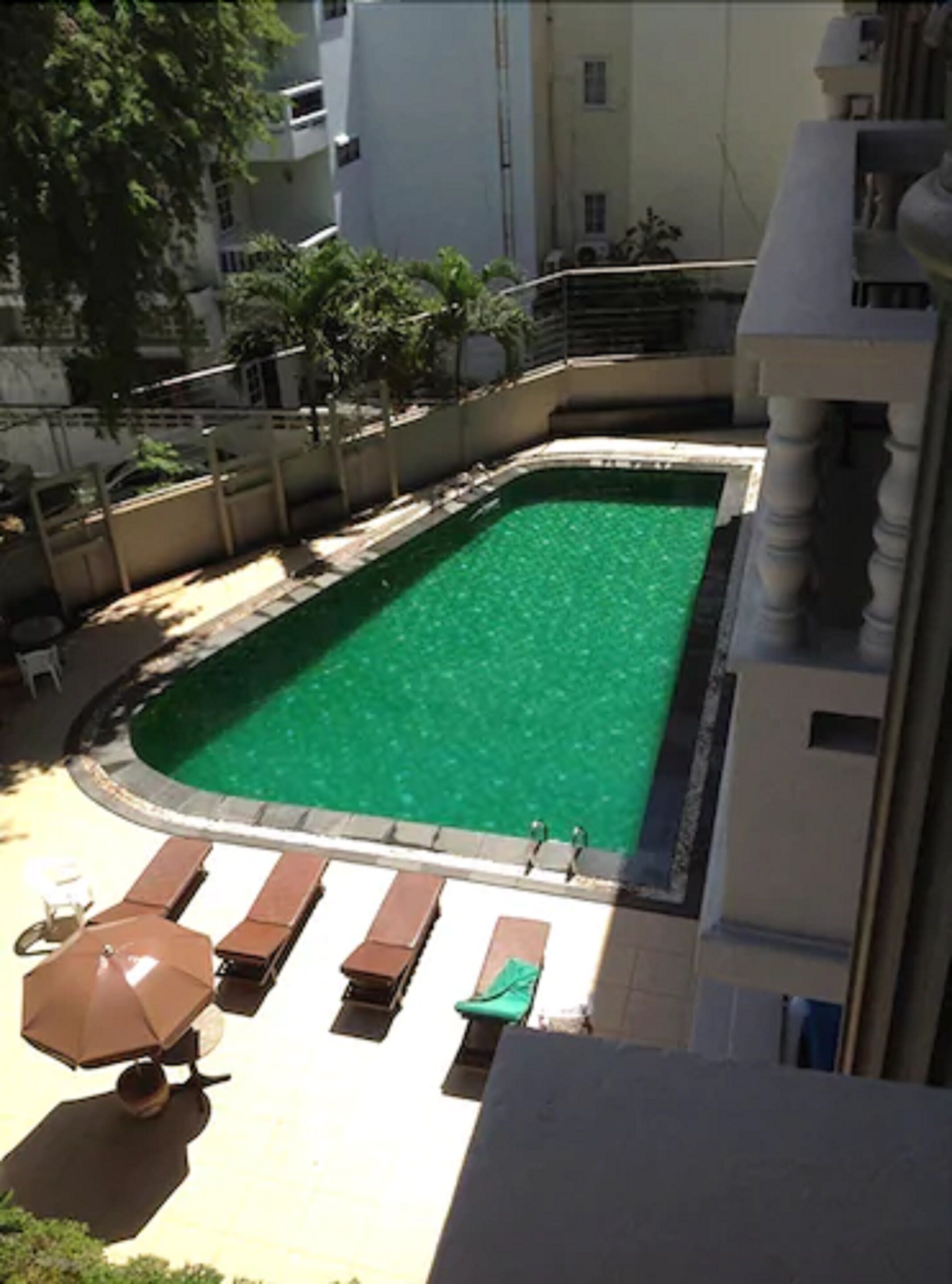 A rectangular swimming pool with a curved edge, surrounded by a low wall and a few lounge chairs.
