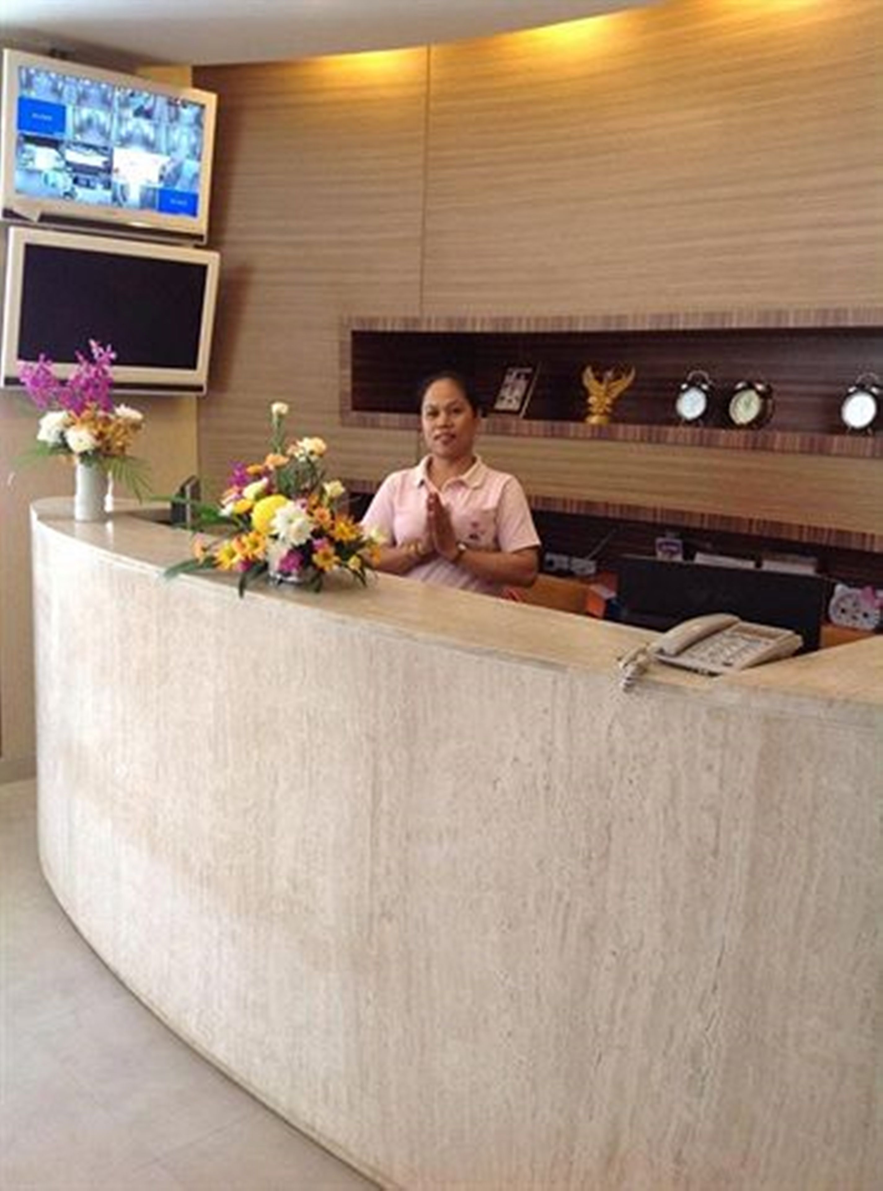 A reception desk with a monitor, a telephone, and a floral arrangement.