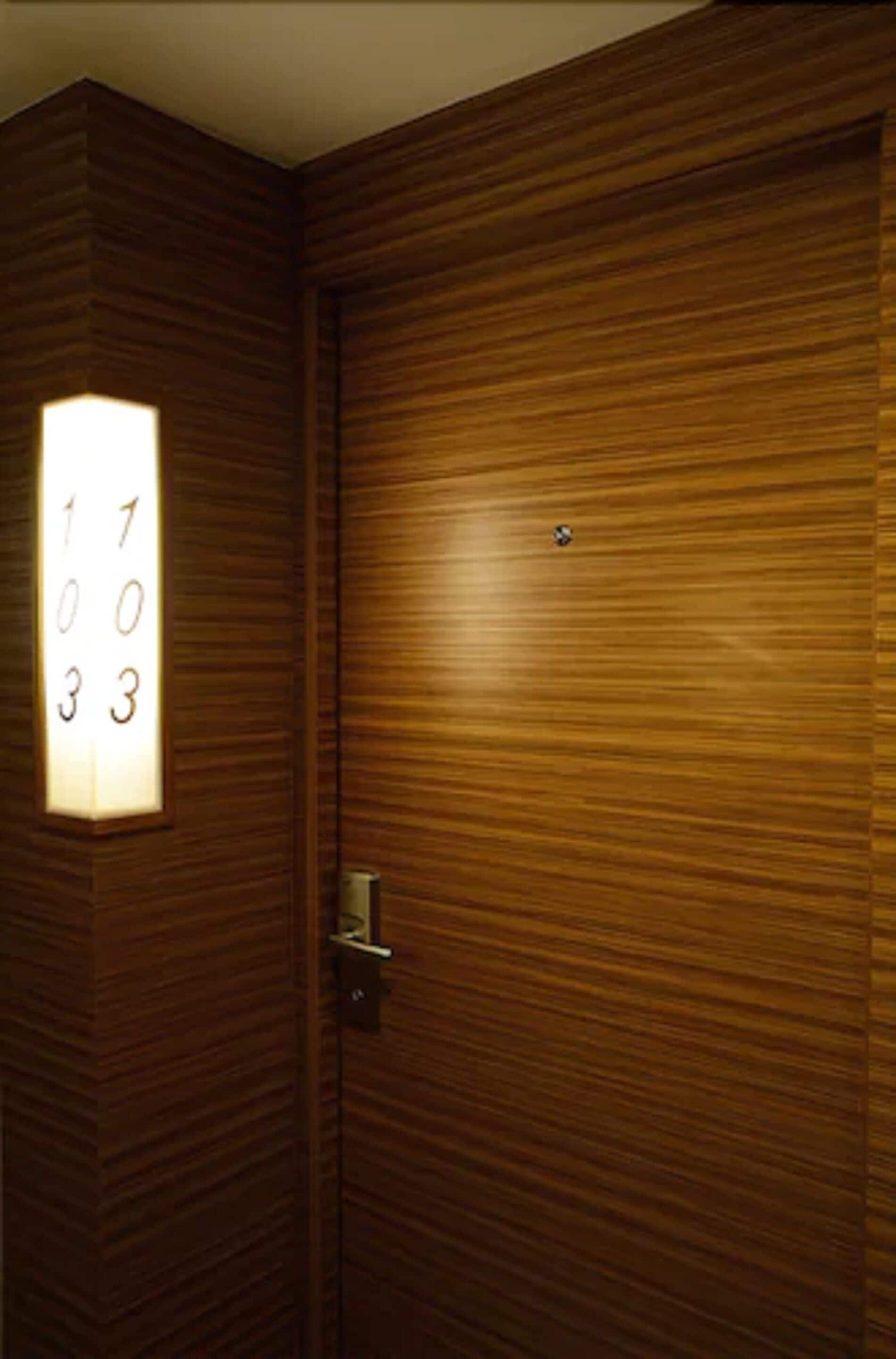 A wooden door with a numerical keypad and a light panel.