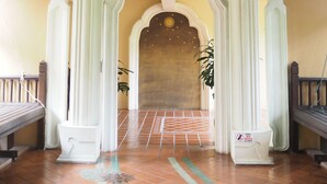 An arched entrance with a tiled floor, white columns, and hanging lanterns. - Villa Thongbura (Pattaya)