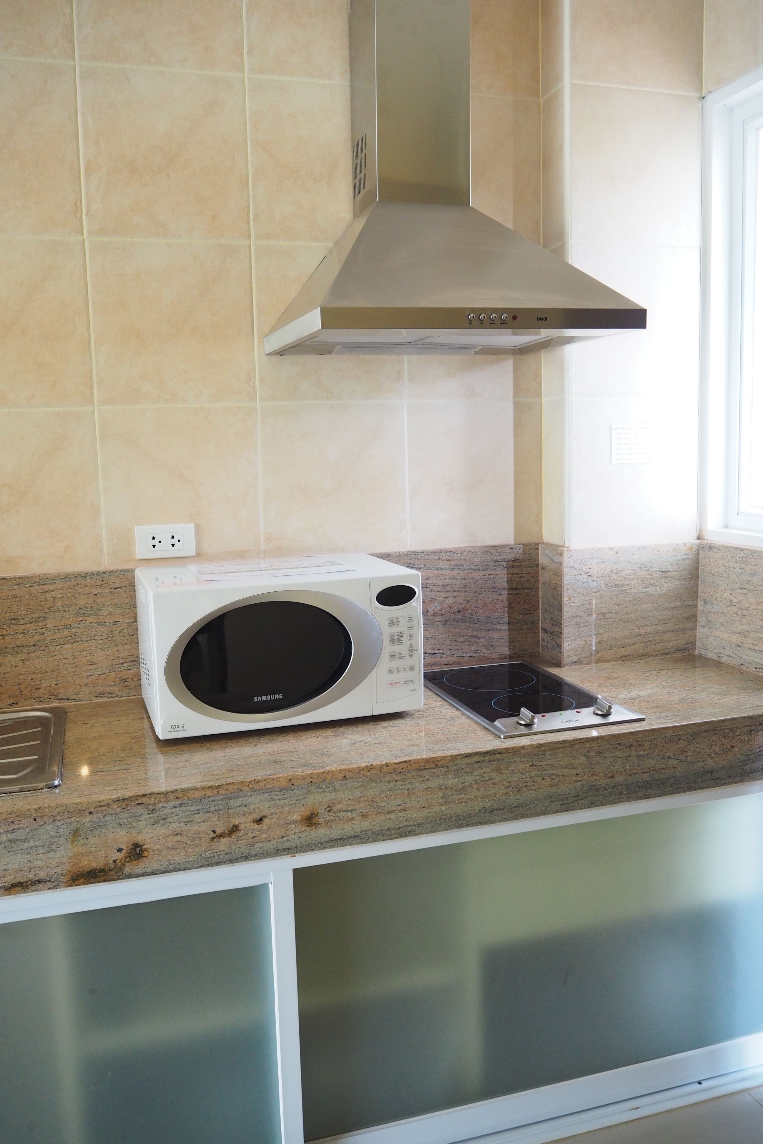 Una cucina con un forno a microonde bianco, una cappa aspirante in acciaio inossidabile e un piano di lavoro in granito.
