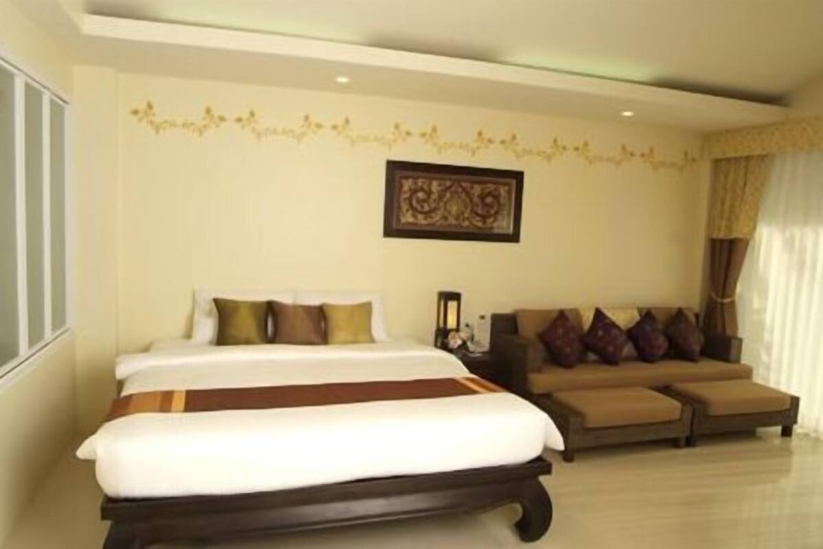 A hotel room with a large bed, a sofa, and a decorative wall piece.