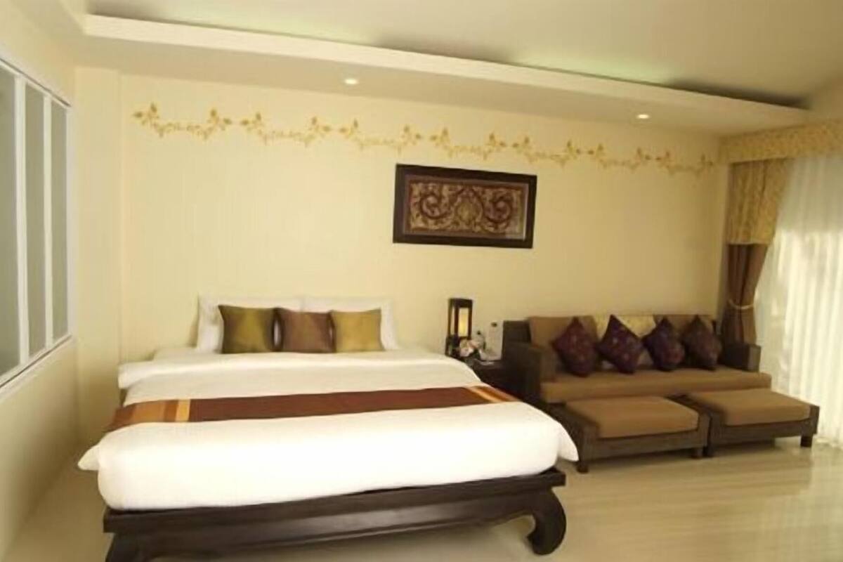 A hotel room with a bed, a sofa, and a decorative wall.