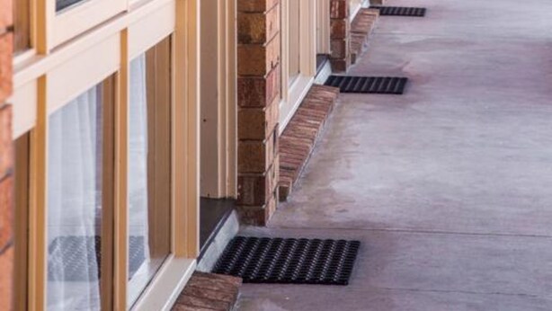 A covered corridor with brick walls and large windows.