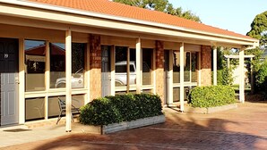 A building with a covered porch, brick walls, and a tiled roof.