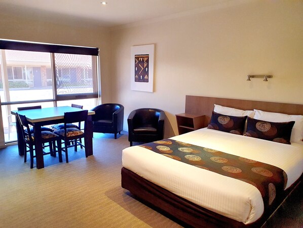 Ein Hotelzimmer mit einem Bett, einem Schreibtisch, zwei Stühlen und einem Fenster.