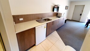 A compact kitchen with a sink, microwave, and a small refrigerator.
