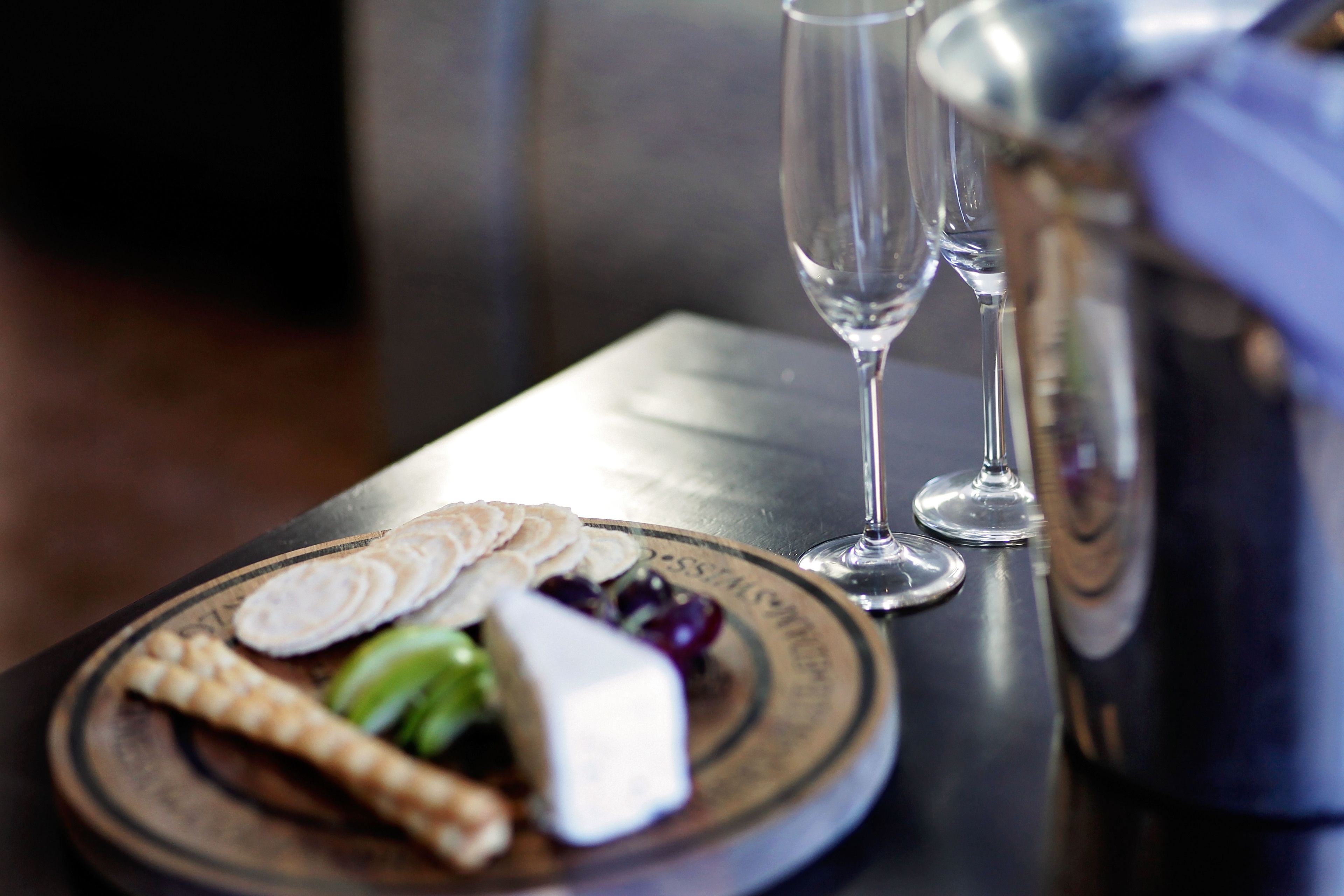A plate of cheese and crackers on a table with two glasses of wine.