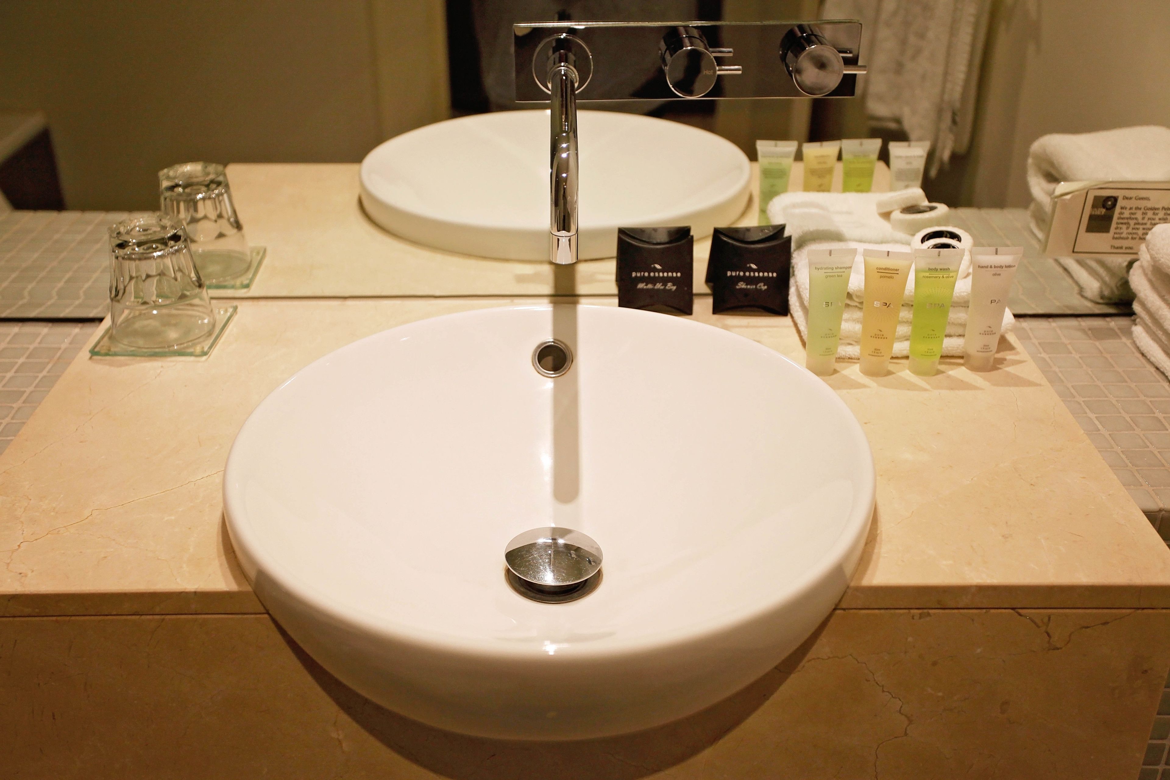 A bathroom with a white sink, a mirror, and toiletries on the counter.