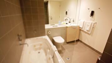 Un baño moderno con bañera, inodoro, lavabo y espejo.