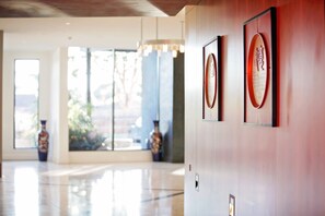 Un vestíbulo moderno con piso pulido, ventanas amplias y jarrones decorativos.