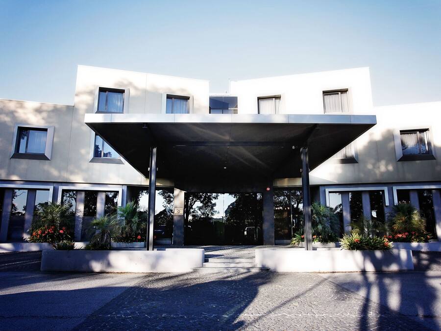 A modern building with a covered entrance, large windows, and symmetrical design.