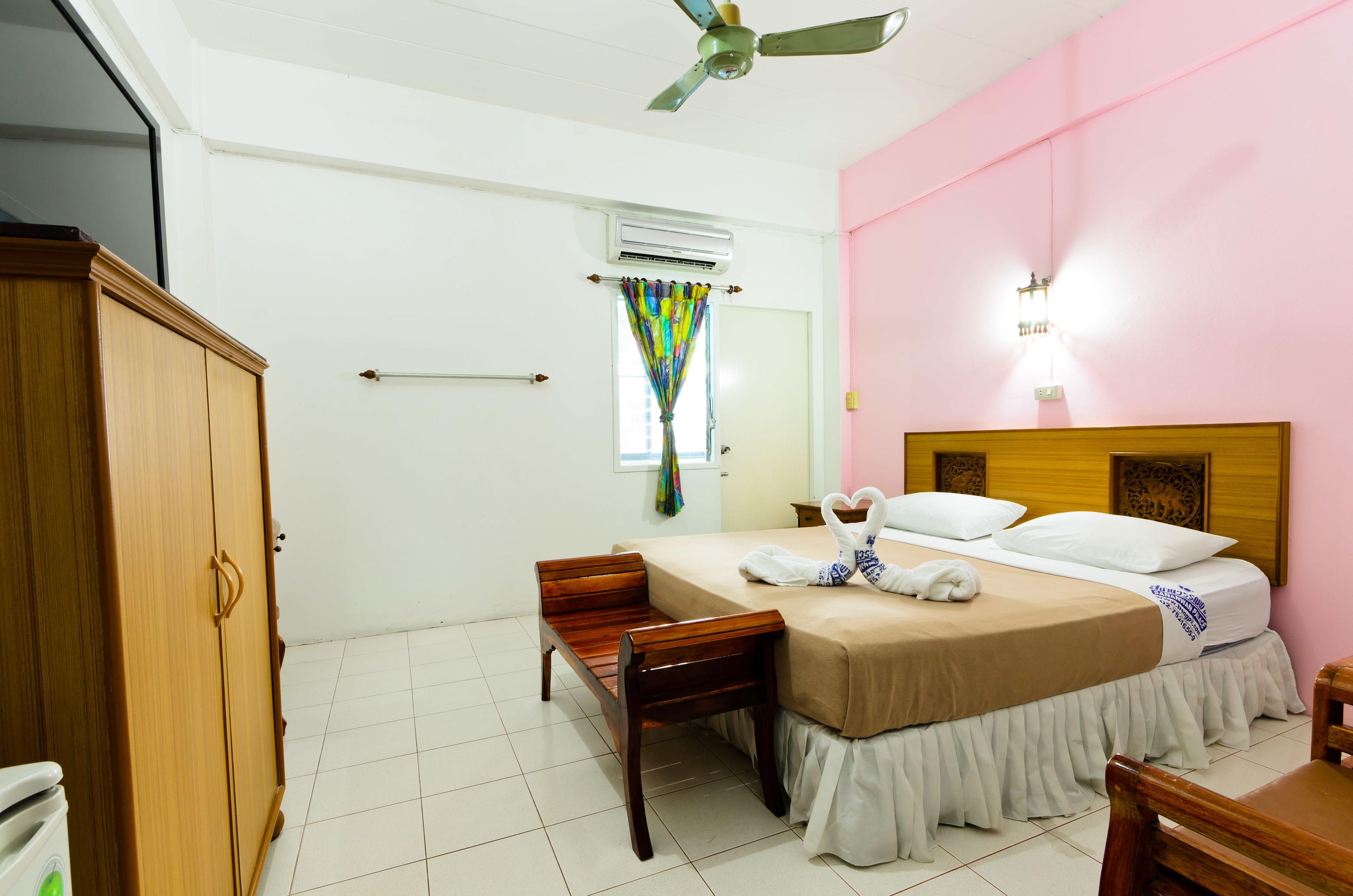 A bedroom with a bed, wooden wardrobe, and a ceiling fan.