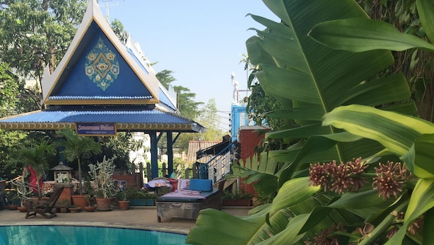 Ein Swimmingpool mit blauer Umrandung, umgeben von Kübelpflanzen und einem Pavillon.