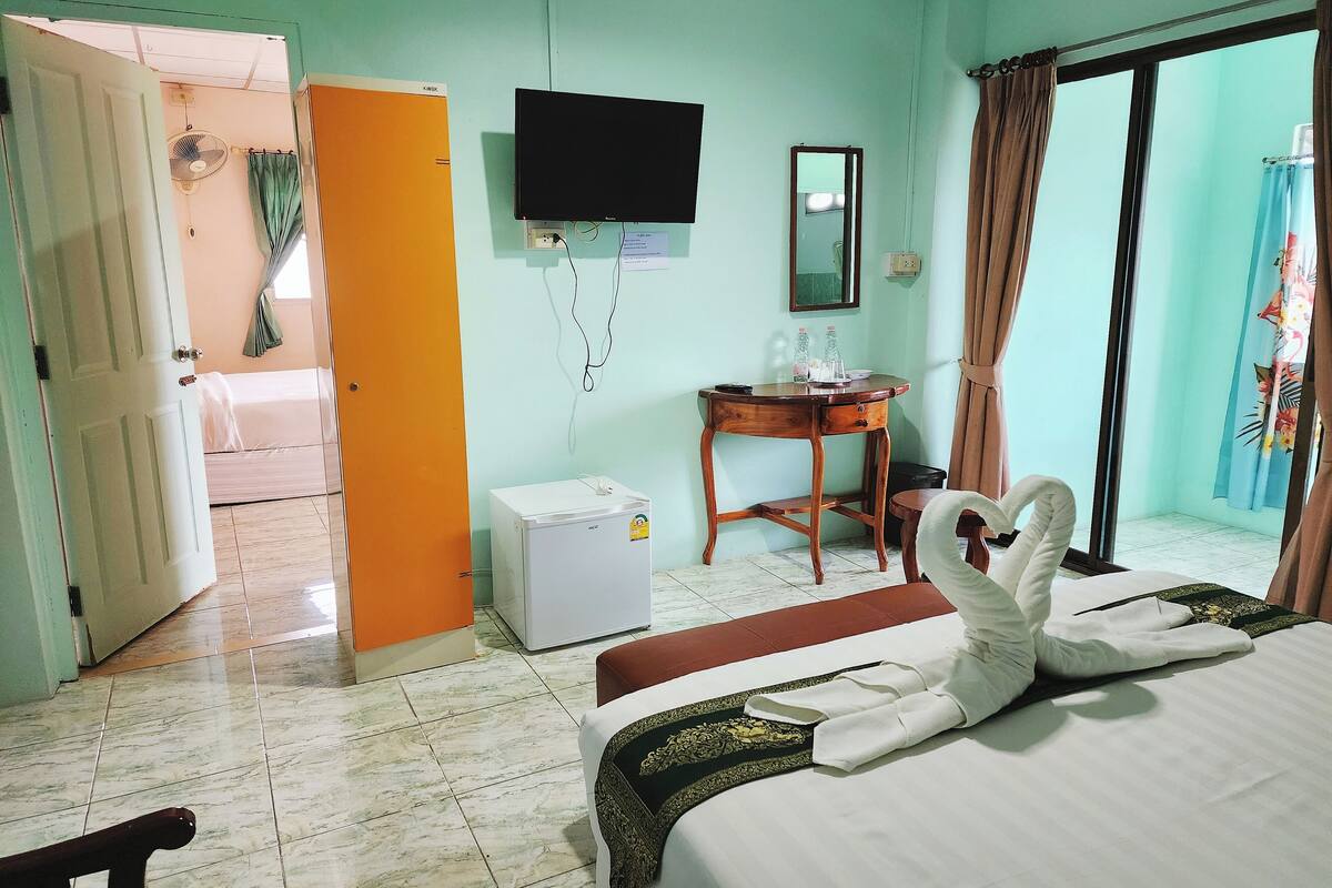 A hotel room with a bed, a desk, a chair, a television, a mirror, and a window with curtains.
