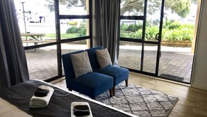 A room with a bed, a blue sofa, and large windows. - Half Moon Bay Motel (Auckland)