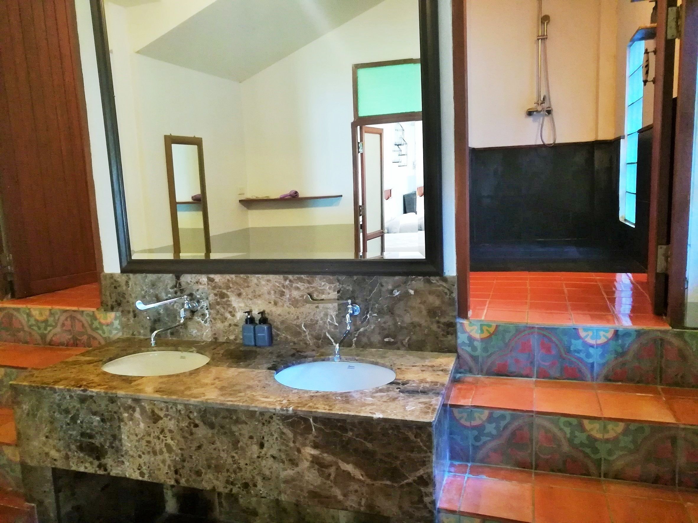 A bathroom with two sinks, a mirror, and a shower.