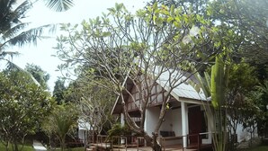 A bungalow with a wooden deck, surrounded by lush greenery and a concrete pathway. - Koh Munnork Private Island (Koh Mun Nork)