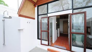 A modern house with a large glass door, a shower, and a tiled patio.