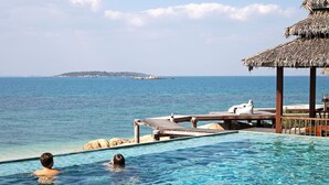 A pool with clear blue water, a wooden deck, and a thatched-roof structure. - Koh Munnork Private Island (Koh Mun Nork)