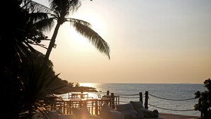 A sunlit outdoor seating area with tables and chairs, overlooking a body of water. - Koh Munnork Private Island (Koh Mun Nork)