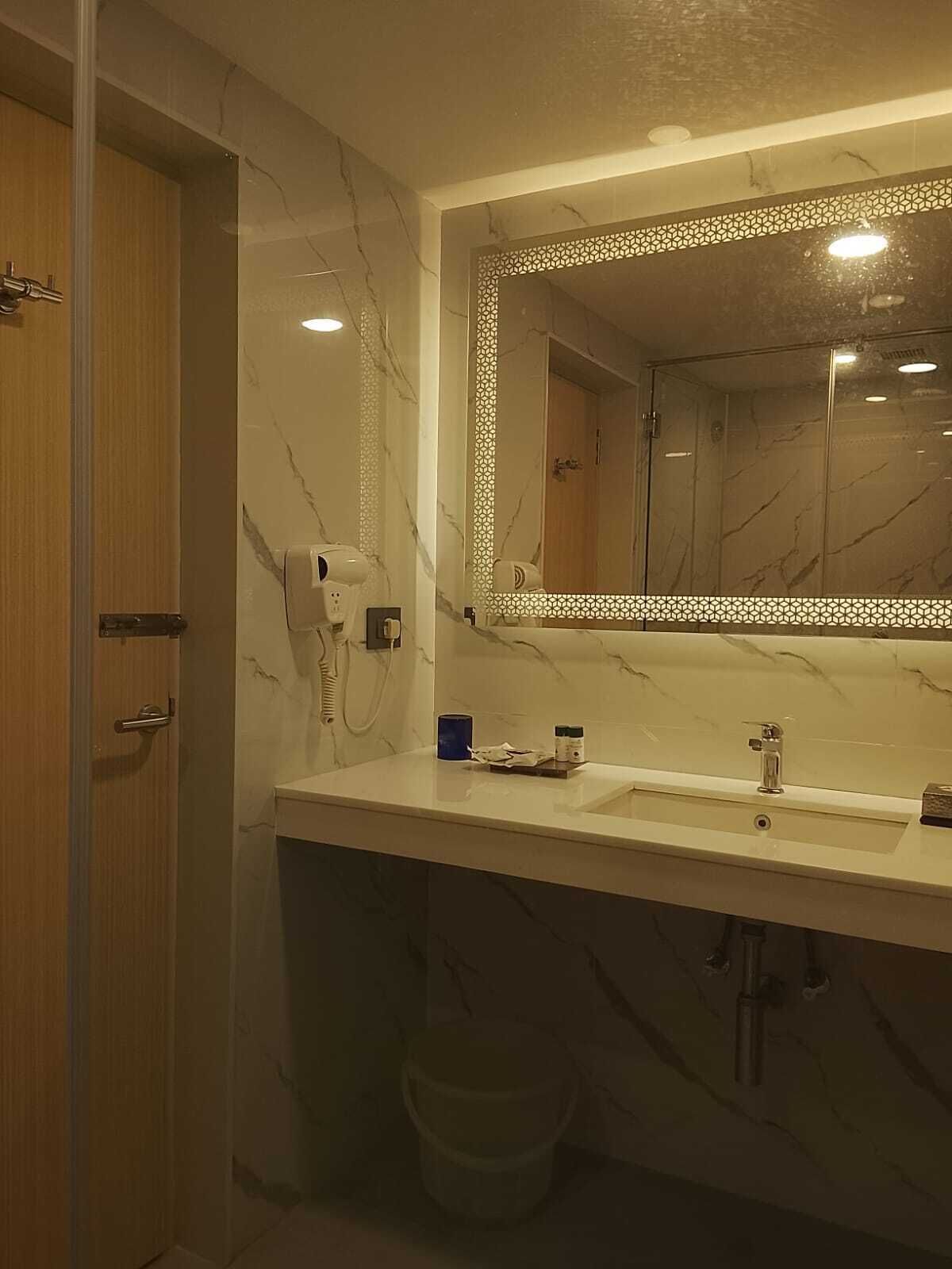 A bathroom with a marble vanity, a large mirror, and a shower area.