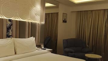 Una habitación de hotel con una cama grande, un escritorio, una silla, una mesita y un ventilador de techo.