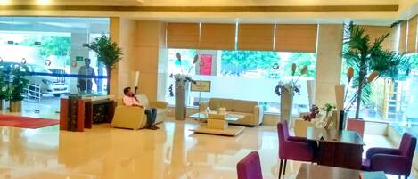 A spacious lobby with a reception desk, seating area, and large windows.