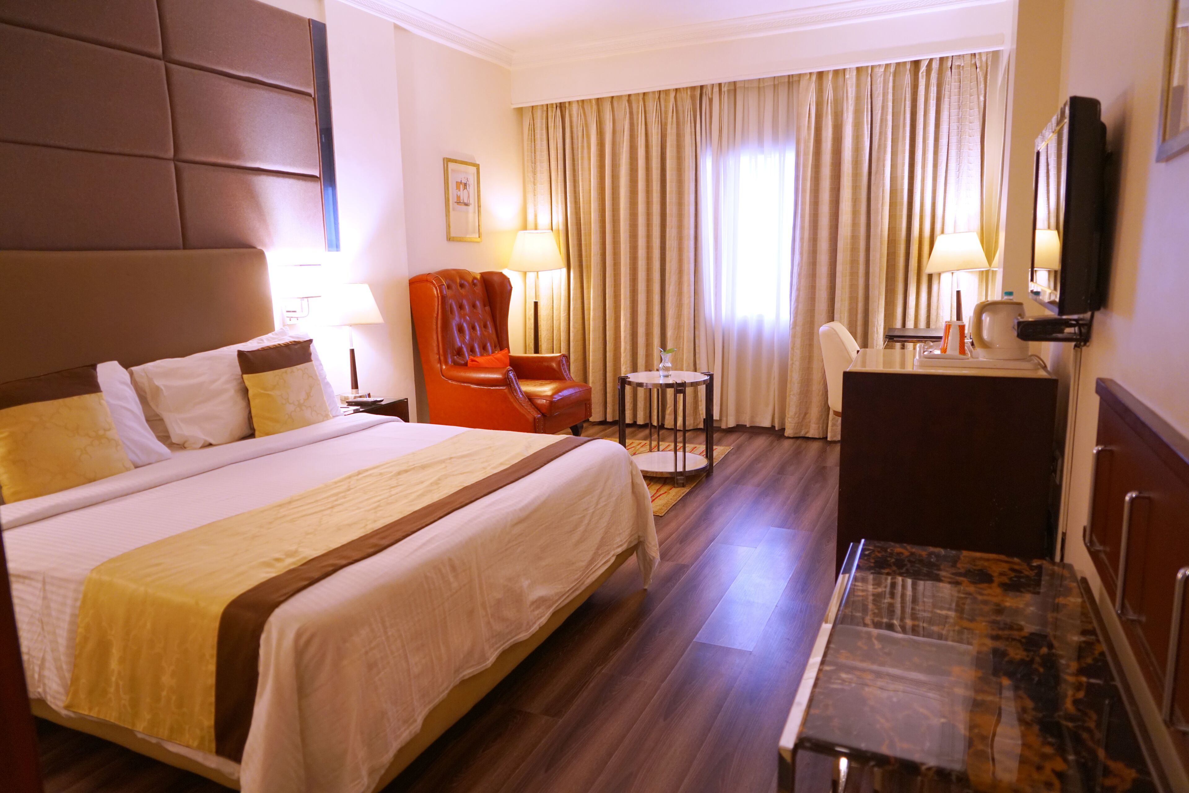 A hotel room with a large bed, a desk, a chair, and a television.